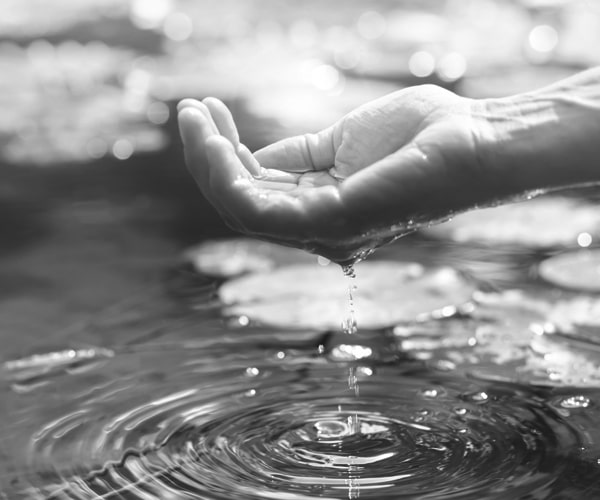Symbolbild für einen Massagekurs: Eine Hand schöpft Wasser aus einem Fluss